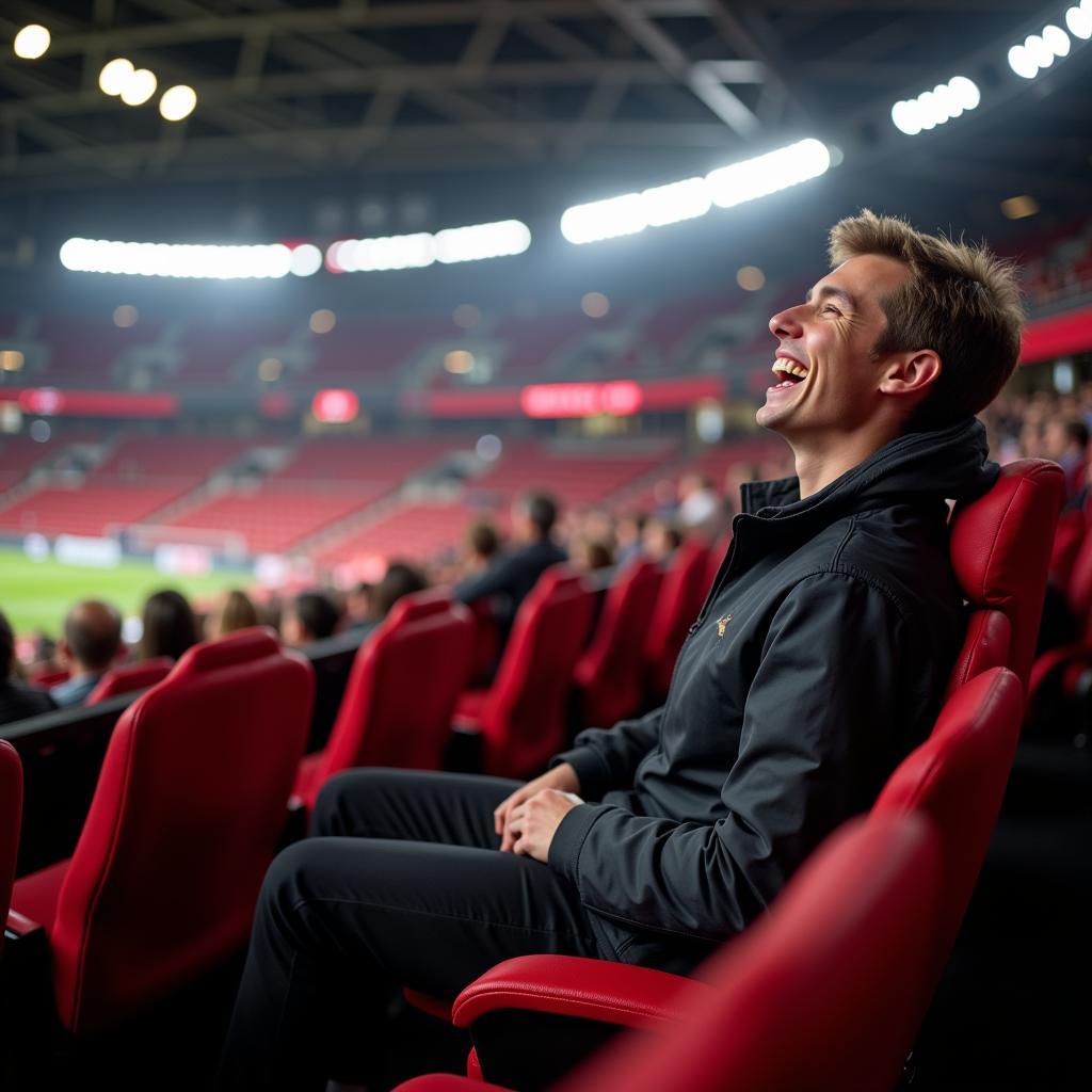 Ein zufriedener Fan genießt das Spiel auf einem aufgearbeiteten Stadionstuhl in Leverkusen.