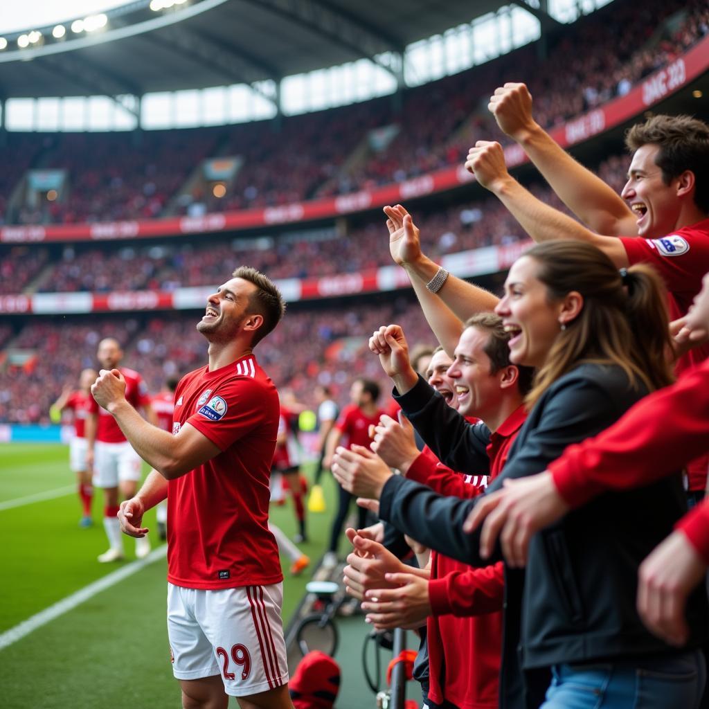 Adrian Berger feiert ein Tor mit den Fans von Bayer 04 Leverkusen.